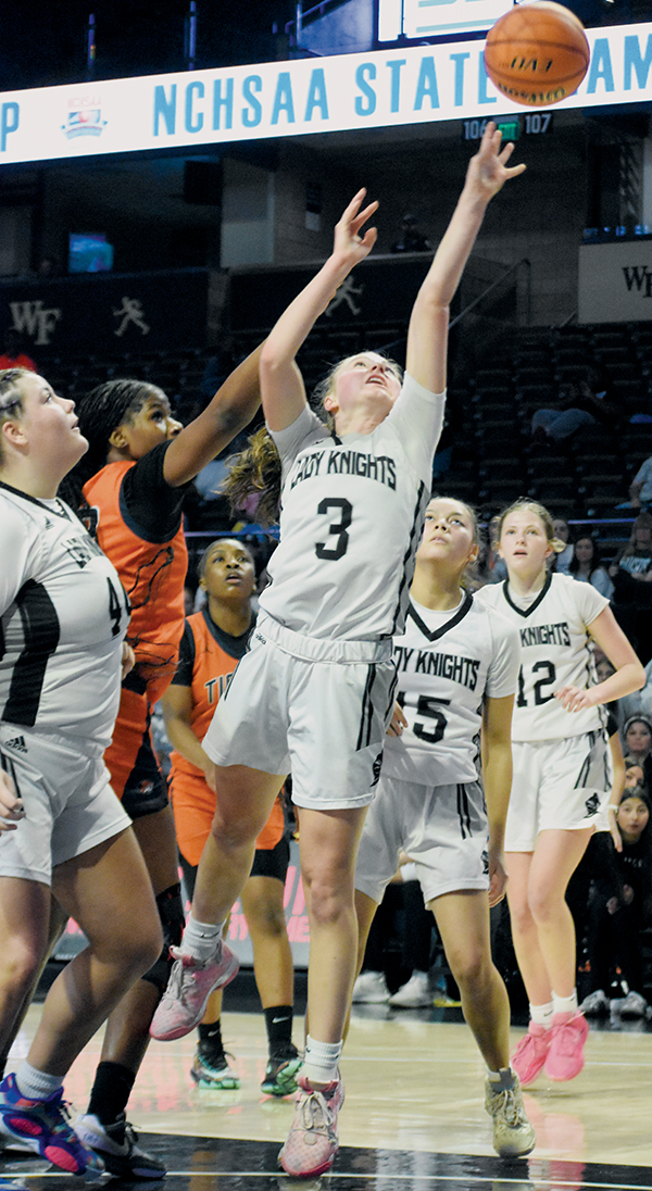 While teammates Bentley Riggins (44), Aaliyah Wolfe (15) and Zaelyn Phillips (12) look on, Robbinsville senior Abby Wehr (3) outpaces Wilson Preparatory Academy's MyAngel Brimage for a second-half basket during March 11's state finals. Wehr led the Lady Knights with 11 points in the game.