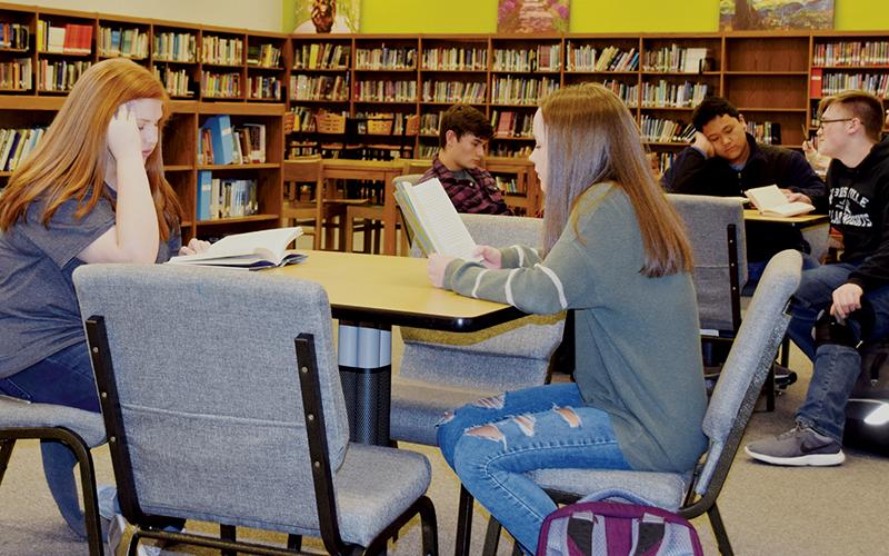 Lilly Lancaster and Charida Willis (front table), as well as Wilhem Crisp, Russell Hooper and Eddie Brooms (back table) persue through some books at Robbinsville High School on Monday. Graham County Schools received a grade of "C" for their literacy levels during the 2018-19 year. Photo by Art Miller/amiller@grahamstar.com