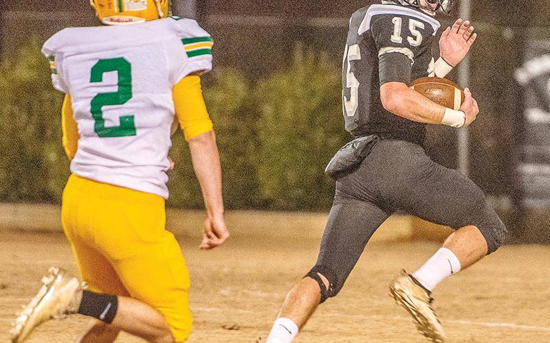 Clayson Lane (15) glances back at Alleghany’s Alex Ingraham midway through his 44-yard touchdown run during Nov. 21’s win over the Trojans.