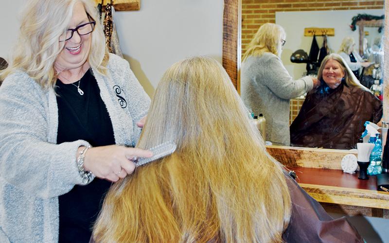 Gina Schuler, owner of Scissors Salon, shares a light-hearted moment with Mariann Miller on Tuesday. Photo by Art Miller/amiller@grahamstar.com