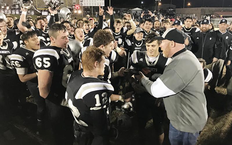 Robbinsville High School principal David Matheson (right) presents Black Knight players (from left) Carlos Wesley, Grady Garland, Kamron McGuire, Clayson Lane and Rylee Anderson with the 1A Western Regional Championship trophy, moments after a 28-14 win over Thomas Jefferson Classical Academy on Friday night. Photo by Kevin Hensley/editor@grahamstar.com
