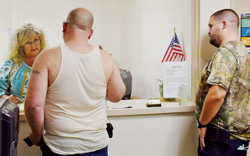 County Clerk Kim Crisp helps customers Lamar Holland (left) and Brandon Barry on Friday. Government offices in Graham County have slowly began reopening to the public, with plenty of precautions in place. Photo by Art Miller/amiller@grahamstar.com