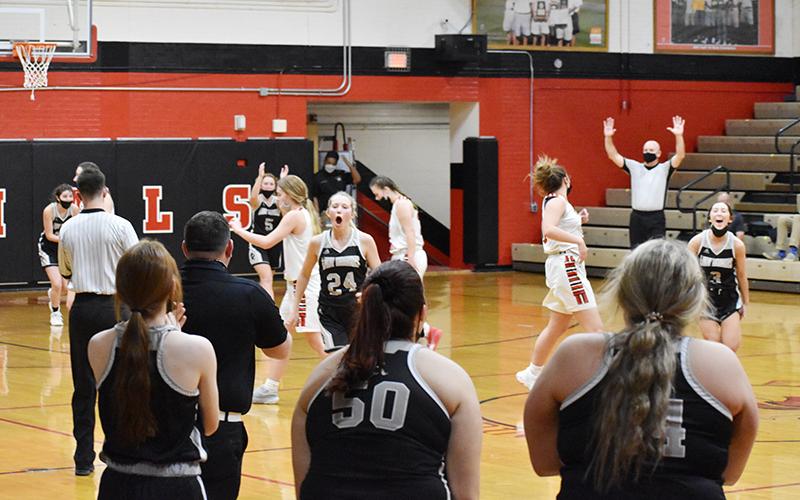 Robbinsville's Kensley Phillips (24) and Gabby Hooper (3) kick off the victory celebration as the official signals the end of the Lady Knights' 72-60 comeback win at East Surry on Thursday night. Photo by Kevin Hensley/editor@grahamstar.com