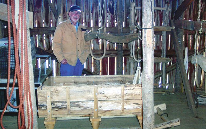Buster Stewart stands with two of his creations: a yoke and a sled. Photo by Marshall McClung/The Graham Star
