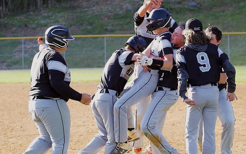 Members of the Robbinsville Black Knights mob Greylen Orr on the first-base line, moments after Orr sliced an opposite-field, walk-off single to give Robbinsville a 4-3, extra-innings victory over Rosman on Friday. Photo by Miranda Buchanan/Robbinsville High School Yearbook