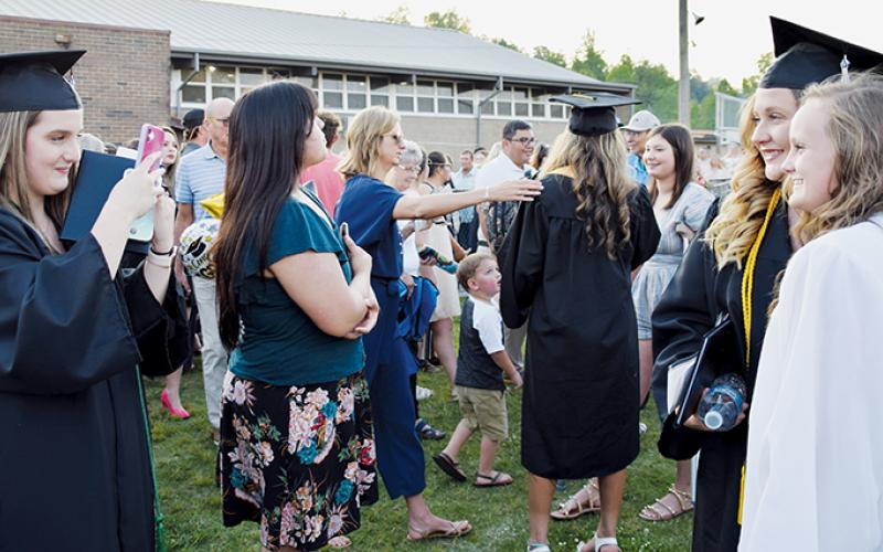 As parents and friends swarmed onto the field at the end of Sunday’s commencement, Adisyn Jenkins helps Sydney Farley and junior marshal Brook Turpin capture a lasting memory.