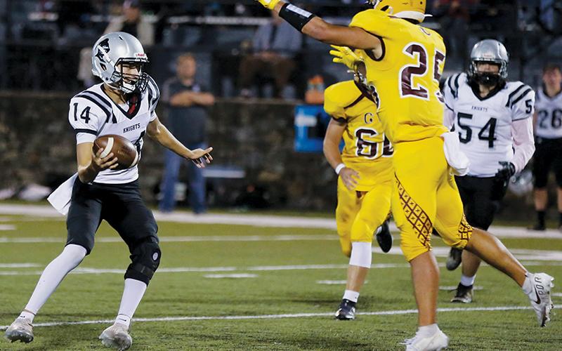 With Cherokee’s Elijah Watty (25) closing in, Robbinsville senior quarterback Dasan Gross scans the field for an open receiver during Friday’s 20-7 loss to the Braves. Photos by Scot McKie/Cherokee One Feather