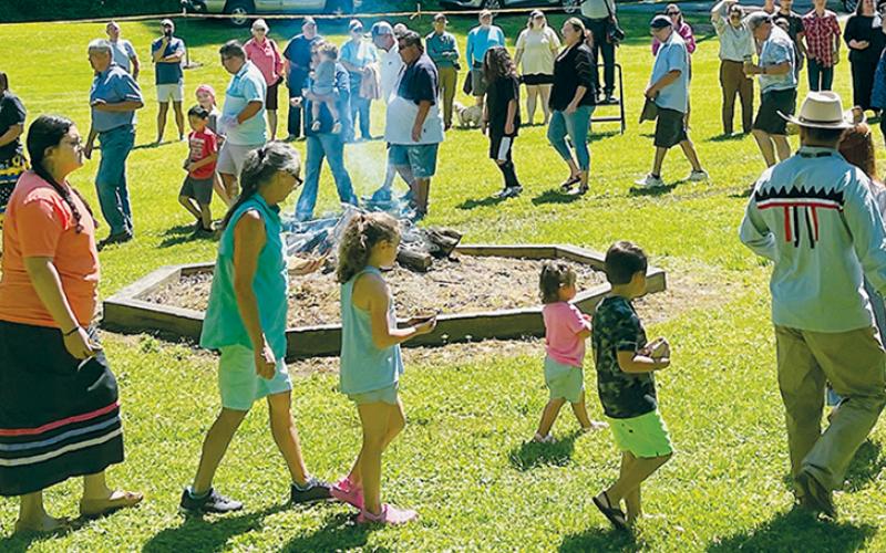 Visitors spread dirt from home on a ceremonial mound during Fading Voices, a  demonstration of Cherokee traditions and culture held on the banks of Little Snowbird Creek on Saturday.