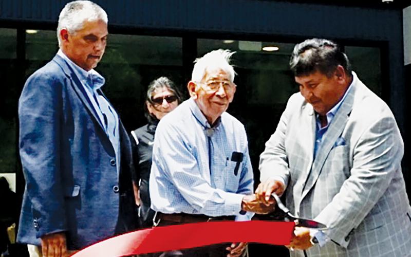 Elder Dan Rattler, assisted by tribal council member Bucky Brown (right), cuts the ribbon at the opening ceremony for the Jacob Cornsilk Community Center in the Snowbird community on Friday. At left is Vice Chief Alan Ensley.
