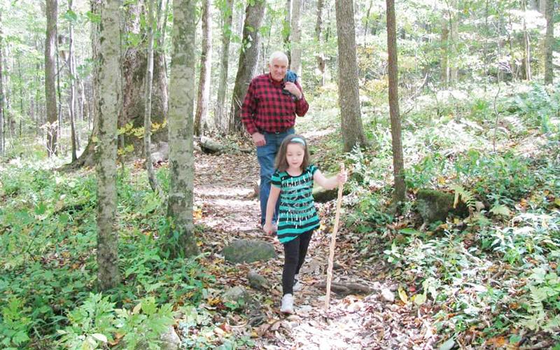 All ages enjoy the woods – including 6-year-old Simone O’Neal, shown walking a trail in Joyce Kilmer Forest with Graham Star columnist Marshall McClung in the background. Photo courtesy of Kim O'Neal/Contributing Photographer