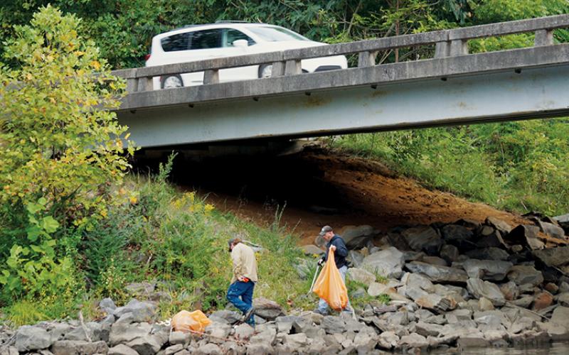 A car passes overhead as volunteers work to clean up the shores of Lake Santeetlah on Saturday.