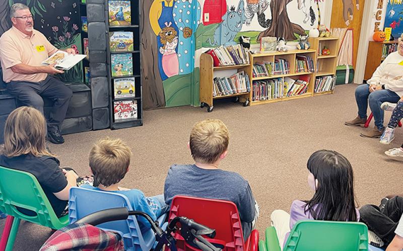 Donnie Orr (left) reads to children at Robbinsville Elementary School’s media center on Friday, as his sister Debbie Orr (right) waits his turn. The siblings were at the school to dedicate a reading nook in honor of their late mother Maxine Orr, who was a teaching assistant at the school for 30 years. Photo by Randy Foster/news@grahamstar.com