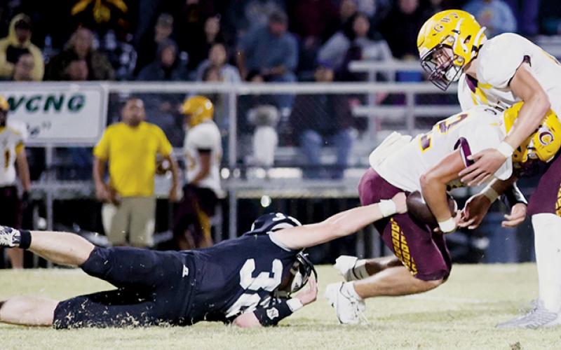 Though grounded, Robbinsville senior Jude Campbell continues his effort to bring down Braves quarterback Kaden Smith on Friday. Photo by Miranda Buchanan/Robbinsville High School Yearbook