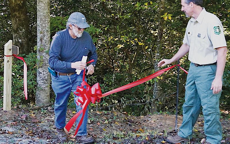 Graham County Commissioner Dale Wiggins (left) cuts the ribbon at a re-dedication ceremony of the  Santeetlah Lake Trail South on Sept. 27. Photos by Randy Foster/news@grahamstar.com