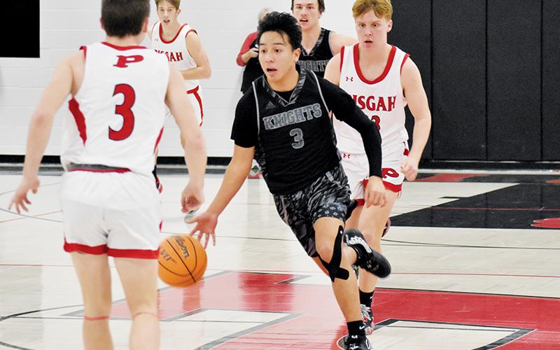 After one of his nine steals, junior shooting guard Xander Wachacha weaves between the defense of Pisgah’s Sawyer Belue (3) and Aaron Clark (back) during  Monday’s loss to the Black Bears. Wachacha had 20 points in the game, 10 of which came in transition. Photos by Kevin Hensley/sports@grahamstar.com