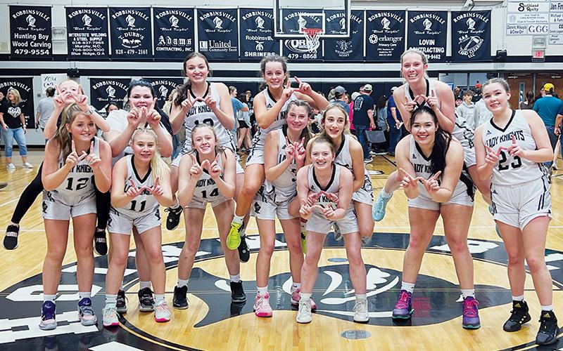 The Robbinsville Lady Knights gather for the final “W” photo they will take on their home court, after polishing off the Draughn Lady Wildcats 65-41 in the fourth round of the state playoffs. All names are listed from left. Front row: Anna York, Suri Watty, Maleah Cox, Abby Wehr, Olivia Lewis, Aubrie Wachacha and Liz Carpenter. Back row: Bella Ford, Bentley Riggins, Katie-Lyn Gross, Desta Trammell, Anna Williams and Kensley Phillips. Photo by Kevin Hensley/sports@grahamstar.com