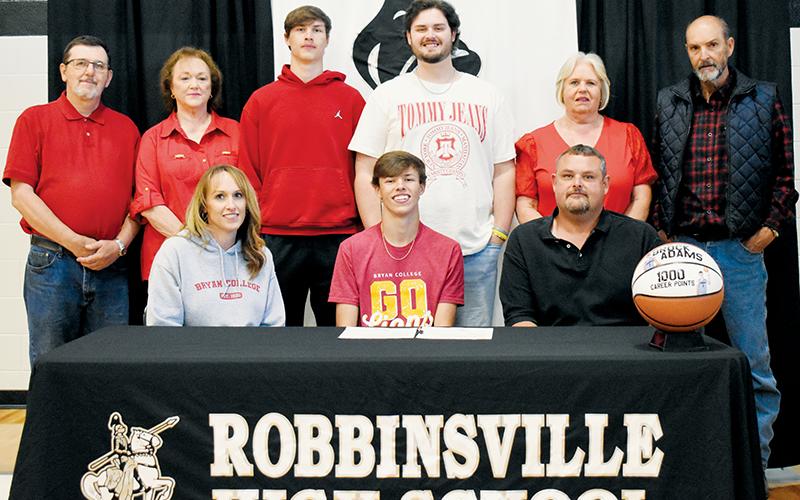 Surrounded by family, Robbinsville senior Brock Adams signed to play basketball at Bryan College on Monday. Sitting with Brock are his mother Andrea and father Tommy. Standing in back (from left) are grandparents Roger and Lisa Orr; brothers, Bryce and Reece Adams; and grandparents Louise and Boyd Adams. Photo by Kevin Hensley/sports@grahamstar.com