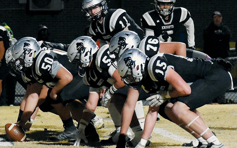 With Bryce Adams in motion, Robbinsville quarterback Donovan Carpenter lines up behind the Knights' offensive line (comprised here of Quinn Jumper, Dayne Webster, Kellen Ensley, Dane Daniels and Roman Jones, from back to front) during Friday's fourth-round playoff game against North Rowan. Consistency up front is one of the driving forces behind the Black Knights reaching the 1A Western Regional Final for the fifth time in six years. Photo courtesy of Faith Broome/Contributing Photographer