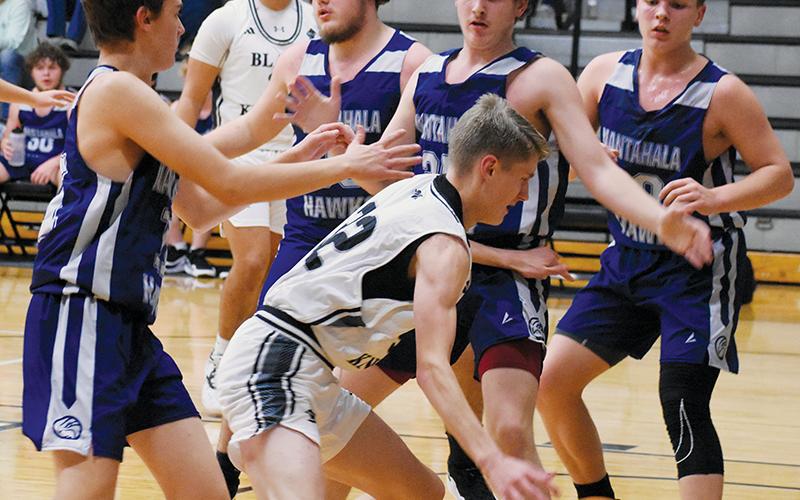 Robbinsville’s Nathan Frederick manuevers through the defense of Nantahala’s Landon Neal (left), Hunter Bryant (center) and Cole McCoy as part of the Knights’ 83-21 trouncing of the Hawks on Tuesday.
