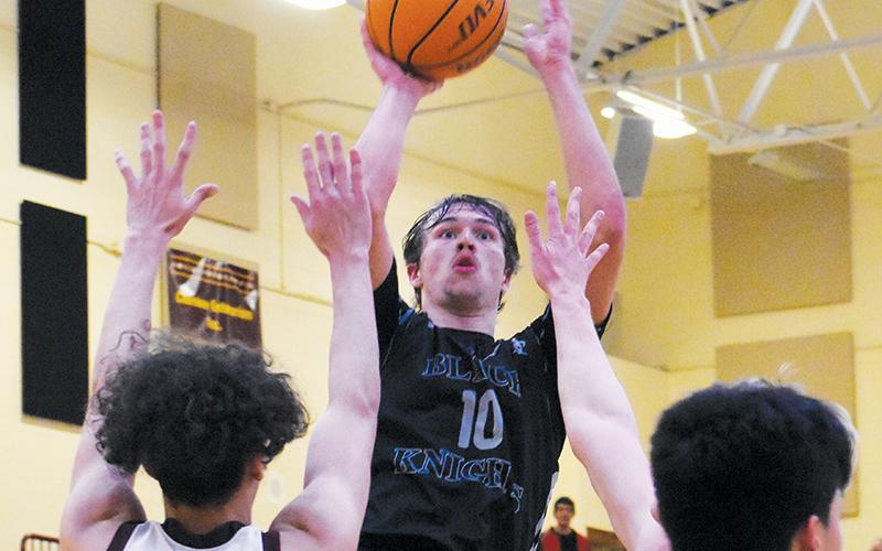 Junior forward Bryce Adams rises above the defense of Cherokee’s Savian Davis (12) and Samuel Hernandez (10) for a second-half basket Tuesday. Including Adams, four Robbinsville players scored in double digits – but could not stop the Braves from winning the Smoky Mountain Conference title. Photos by Kevin Hensley/sports@grahamstar.com