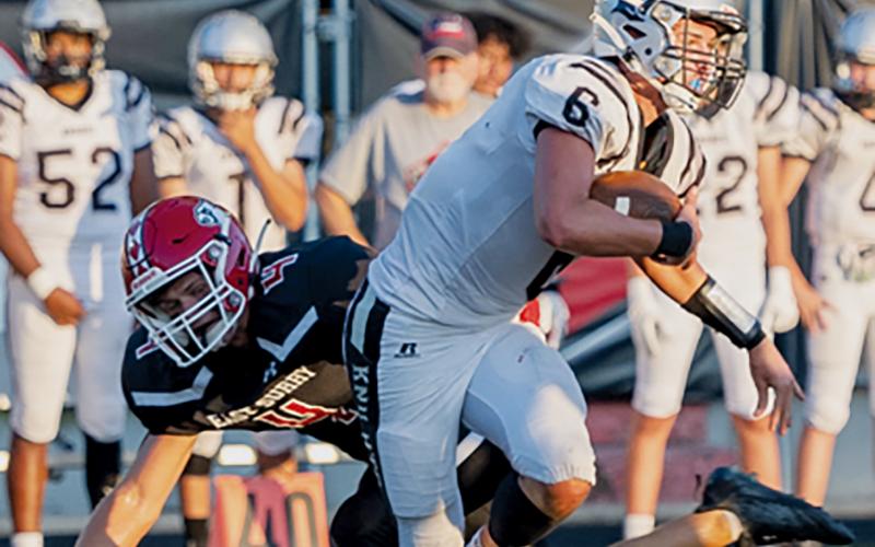 Robbinsville quarterback Bryce Adams breaks away from the pursuit of East Surry’s Luke Bruner during Friday’s 21-19 loss to the Cardinals. Photos courtesy of JR Willoughby Photography