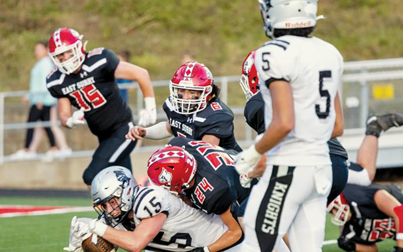 Despite being brought down by East Surry’s Porter Gibson, Roman Jones stretches for positive yardage during Friday’s season opener.