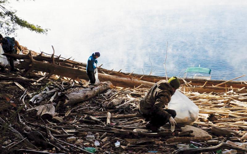 As a mist rises off the water, volunteers sift through garbage strewn about a bank that normally is underwater during warm months on Fontana Lake during last month’s clean-up. Photos courtesy of Brandon Jones/Fontana Village Marina