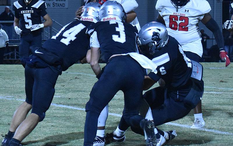 Robbinsville's Cameron Allison (14), Luke Lovin (3) and Bryce Adams (6) combine forces to drop Thomasville's Keshawn Carpenter during Friday's first-round playoff game. Photo by Bella Eddings/The Graham Star