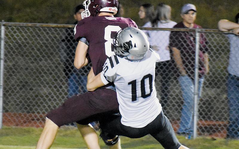 Tanner Hedden wraps up Devils quarterback Owen Medlin for a sack to end the first half of Friday’s win.