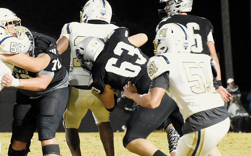 With Tytan Teesateskie (72) running interference,  Robbinsville's Avery Webster (63) wraps up T.C. Roberson's Tariq Sibert on Friday.