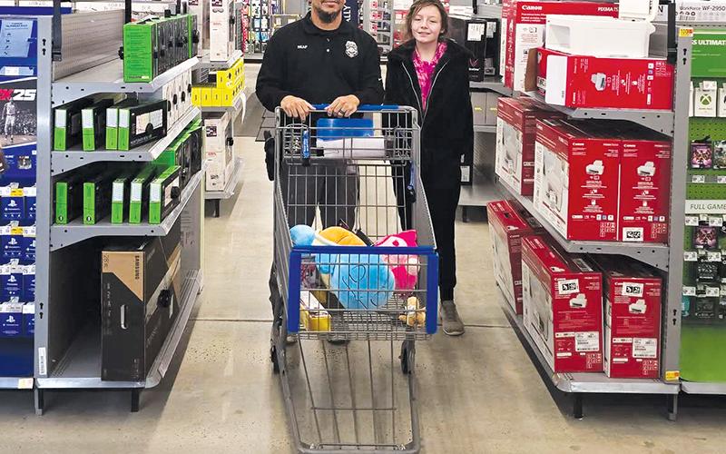 Graham County’s officers took local children to the  Murphy Walmart for the annual “Shop with a Cop” on Dec. 11. Here, Robbinsville Elementary School  Resource Officer Josh Reap helps a member of the program gather Christmas presents. Photo courtesy of Graham County Sheriff's Office