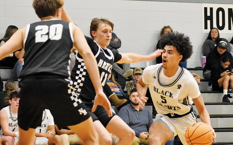 Senior Darion Ledbetter (5) works into the paint and looks to split the defense of North Buncombe’s Cole Edmonds (11) and Tripp Switzer (20) on Jan. 8. Photo by Jacquline Gayosso/The Graham Star