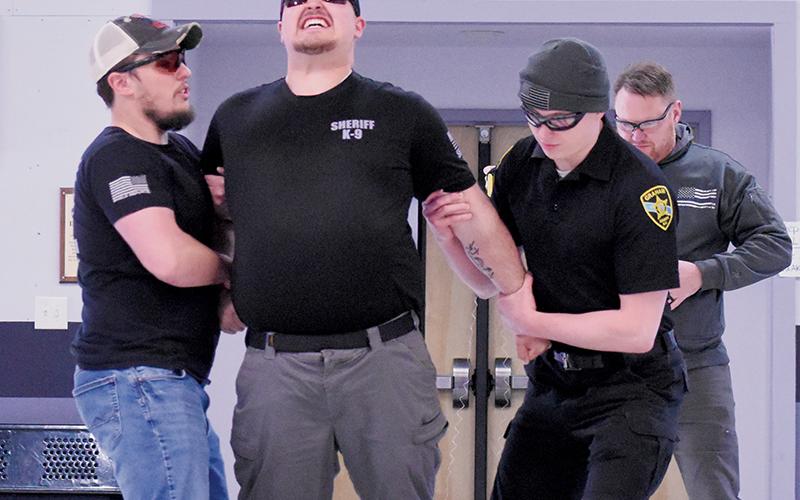 Reality sets in for Taylor Rennoldson as a Taser makes contact at Friday’s certification course. Holding Rennoldson are deputies  Logan Howarth (left) and Justin Stewart; chief detective Travis Brooks is in back, moments after deploying the Taser.