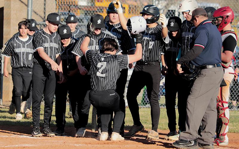 Freshman Easton Shuler (2) stomps onto home plate while being greeted by his  teammates after hitting a two-run homer Friday against Andrews. The long ball was part of a successful comeback bid for the Black Knights against the Wildcats. Photo by Kyla Garland/The Graham Star