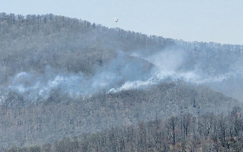 A helicopter flies over the Haoe Lead Fire, preparing to drop water from nearby Lake Santeetlah onto the widespread flames. Photo courtesy of Tory Lynnes/U.S. Forest Service