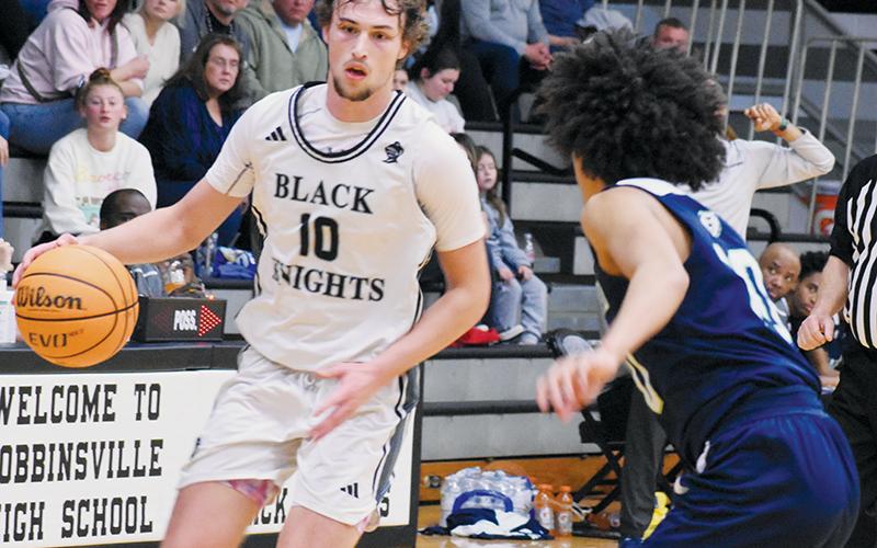 Bryce Adams looks for a way to evade the defense of Bradford Preparatory  Academy’s Isaiah Poston during the first round of the state playoffs Feb. 25. Adams was recently named the Smoky Mountain Conference Boys Player of the Year. Photo by Bella Eddings/The Graham Star