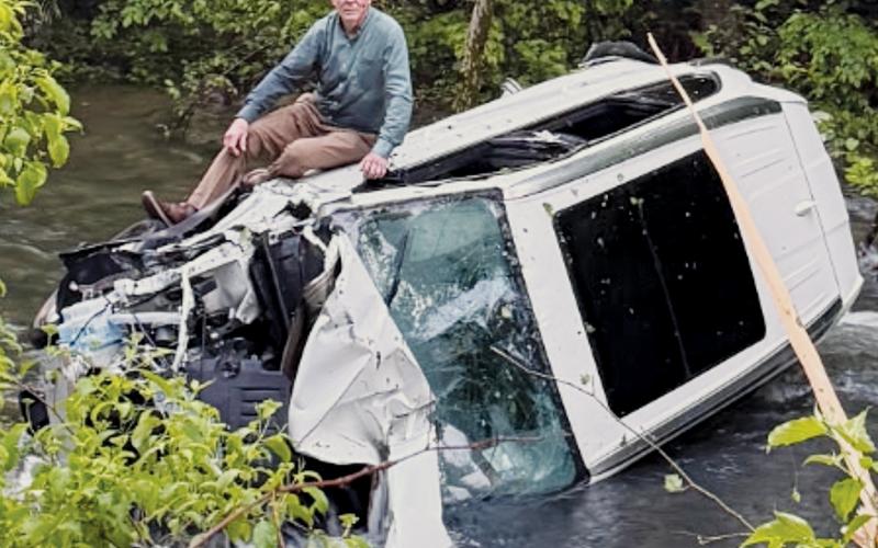 After his May 13 accident, Andrews dentist Dr. James Vollmer, DDS sits atop his wrecked vehicle while waiting for assistance from Graham County Fire and Rescue.