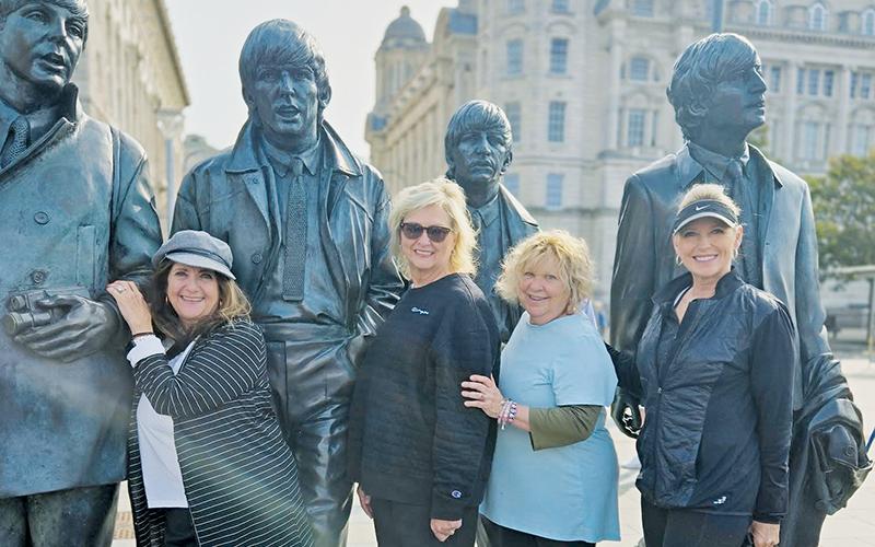 Latresa Phillips, Barbie Adams, Pricella Andrews-Maury and Kim Waldroup (from left) pose with Beatles statutes during the writer's overseas trip earlier this month.