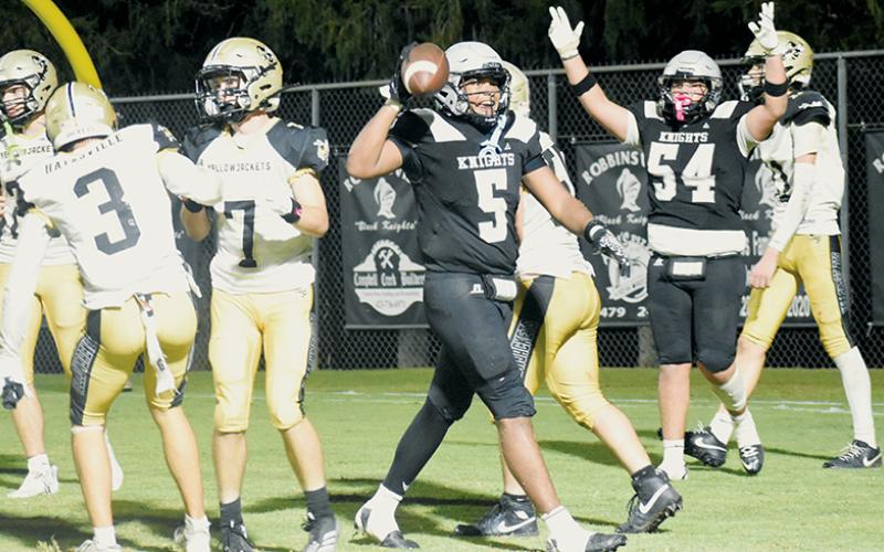 As Kellen Ensley (54) signals in the background, Robbinsville's Kyzik Teesateskie prepares to toss the ball to an official after completing the hat trick during Friday's divisional opener against Hayesville. Photo by Lexie Anderson/The Graham Star