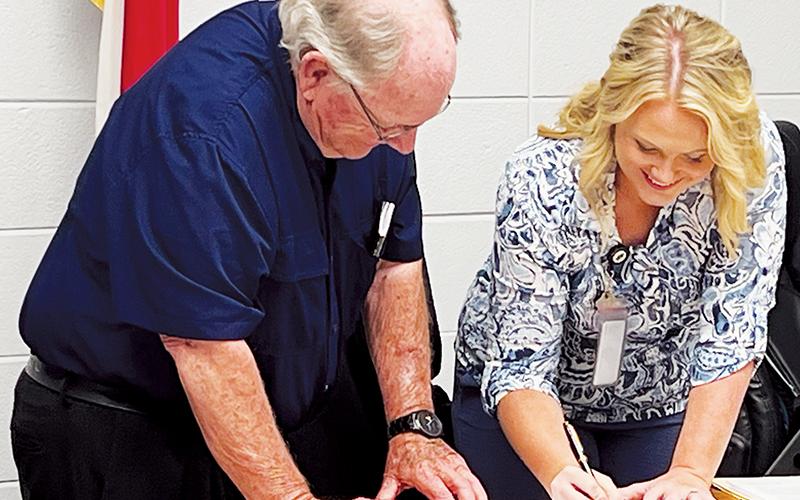 Board of Education Chair Rodney Nelson (left) and Commission Chair Meggan Smith were all smiles while signing a contract Aug. 5, which allows the county to purchase school-owned land to build a justice center.