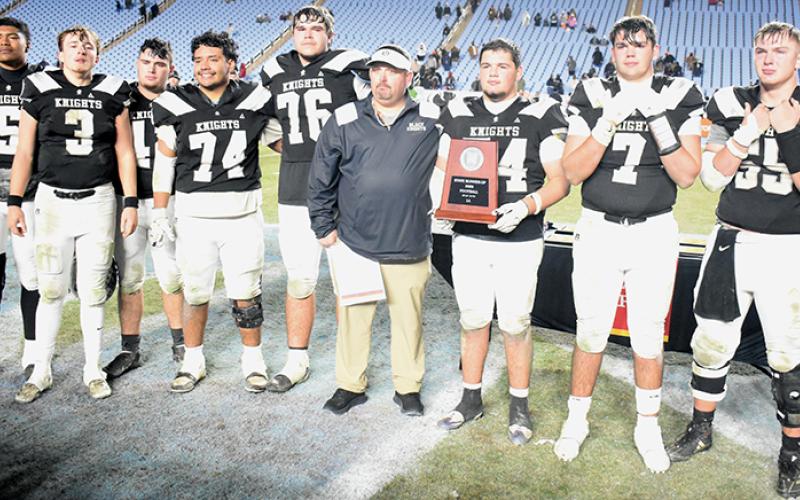 Members of the Robbinsville Black Knights fight back tears of disappointment Dec. 11, after being handed the 1A state runner-up trophy following a 9-8 loss in the championship game to Wilson Preparatory Academy. From left are Kyzik Teesateskie, Luke Lovin, Ryelon Waldroup, John Dominguez, Dane Daniels, head coach Lucas Ford, Kellen Ensley, Isiac Collins and Kasen Buchanan. Photo by Kevin Hensley/sports@grahamstar.com