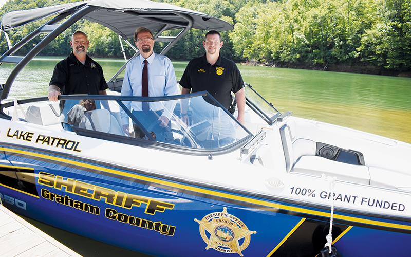 Graham County Sheriff Brad Hoxit, U.S. Rep. Chuck Edwards (R-Hendersonville) and Swain County Sheriff Brian Kirkland (from left) stand inside the $80,000 search and rescue boat that was obtained under the federal  Community Project Funding Grant on Aug. 15. The purchase of the boat and the recent acquisition of a $36,000 have both been questioned by the community. Photo by Kevin Hensley/editor@grahamstar.com