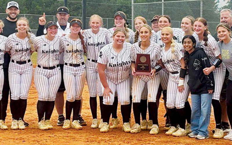 The Robbinsville Lady Knights gather around the 2026 1A Western Regional championship plaque, minutes after clinching the program's first-ever state-title appearance. Photo courtesy of Sasha Watty/Contributing Photographer
