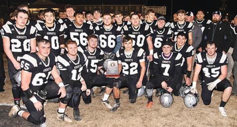 Members of the Robbinsville Black Knights crowd around the 1A Western Regional Championship trophy moments after defeating the Thomas Jefferson Classical Academy Gryphons 28-14 on Friday night. Photo by Byron Housley/The Graham Star