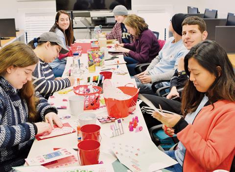 Madison Coffey, Isabelle Handy, Daniella Giese, Ashley Ruston, Catherine Cloutier, Matthew Griffin, Craig Bucci and Slesha Tuladhar (clockwise from bottom left) work on Valentine’s Day cards for troops stationed overseas Friday at the Snowbird  Community Library. Photo by Art Miller/amiller@grahamstar.com