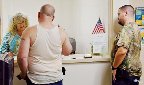 County Clerk Kim Crisp helps customers Lamar Holland (left) and Brandon Barry on Friday. Government offices in Graham County have slowly began reopening to the public, with plenty of precautions in place. Photo by Art Miller/amiller@grahamstar.com