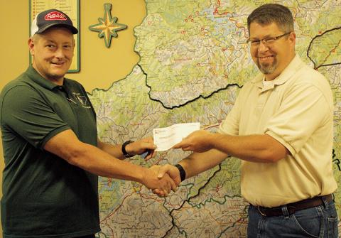 Graham County Rescue Squad Commander Jeff Millsaps (left) accepts a $12,000 donation to the rescue squad from Miatas at the Gap organizer Josh Hankins on Saturday. The annual event alternates donations between the Graham County and Blount County, Tenn. rescue squads. Photo by Charlie Benton/news@grahamstar.com
