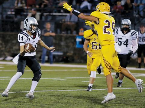With Cherokee’s Elijah Watty (25) closing in, Robbinsville senior quarterback Dasan Gross scans the field for an open receiver during Friday’s 20-7 loss to the Braves. Photos by Scot McKie/Cherokee One Feather