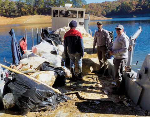Three volunteers in the annual Fontana Lakeshore Cleanup haul garbage aboard their vessel. The event was held from Friday-Sunday and removed more than 170,000 pounds of trash from the lake.