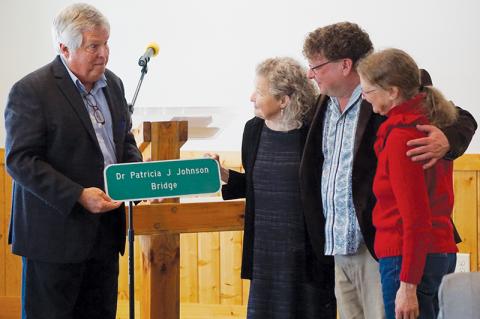 Dr. Patricia Johnson (center) receives a replica of a bridge sign from board member Dirk Cody of the N.C. Board of Transportation (left) at a reception in her honor at Cedar Cliff Church on West Buffalo Road on Saturday. Right of her are her nephew Jeremy Sims and her sister Sarah Johnson Sims. Photos by Randy Foster/news@grahamstar.com